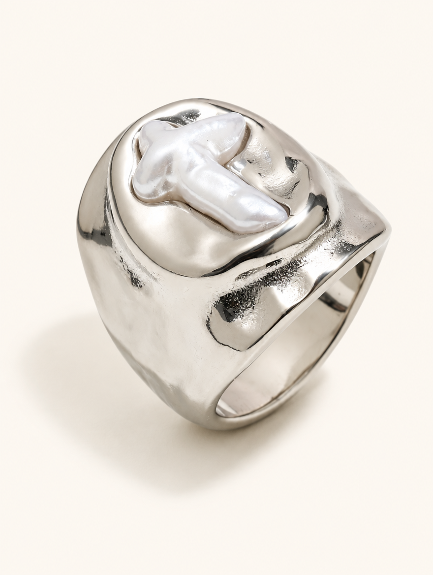 Silver chunky pearl cross ring on a neutral background