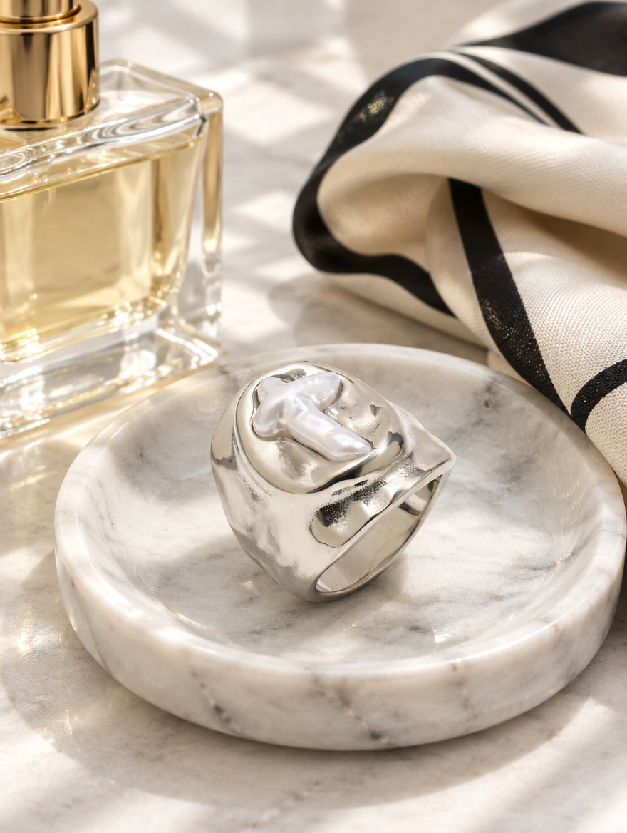 Silver chunky pearl cross ring in a small dish with styling props