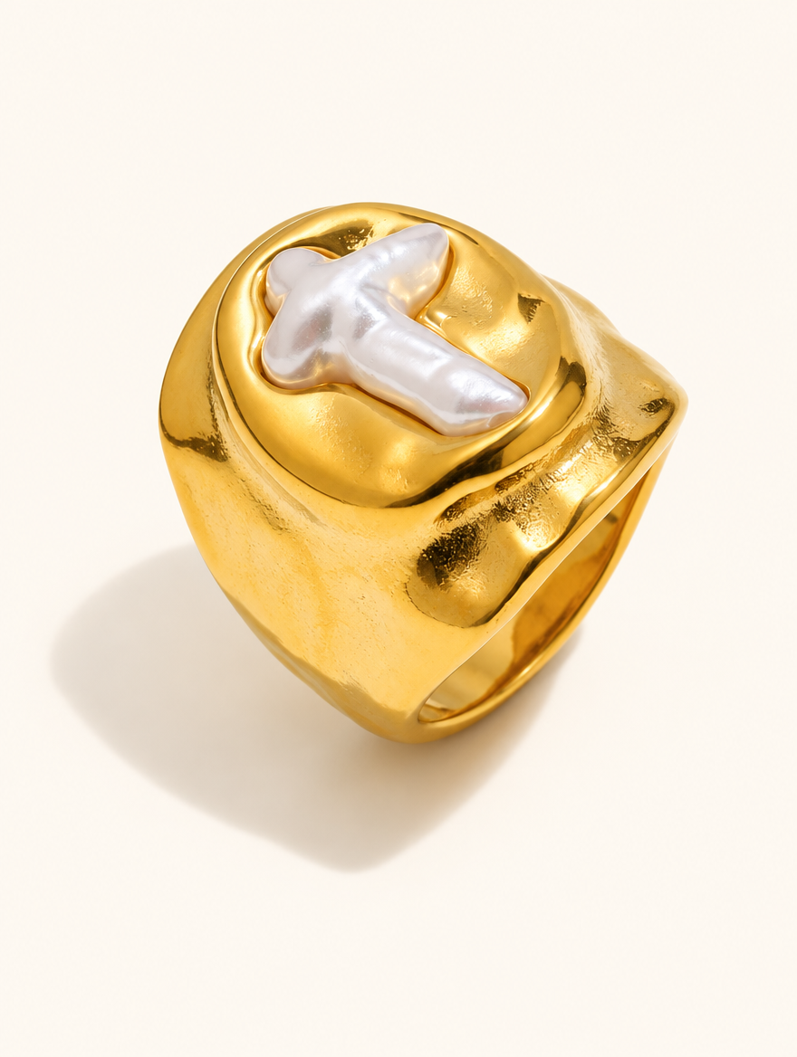 Gold chunky pearl cross ring on a neutral background