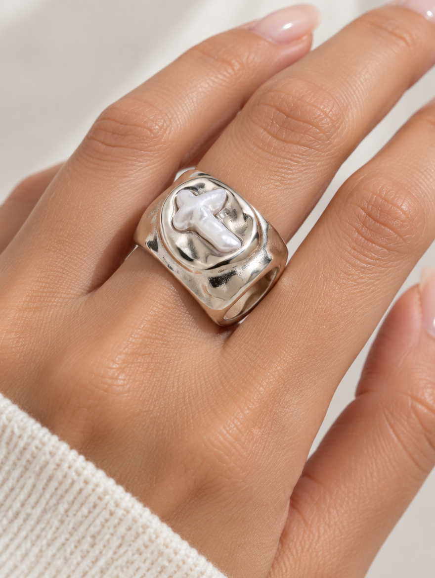 Woman wearing a silver chunky pearl cross ring on her finger