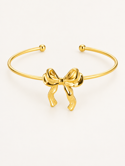 Gold bow open cuff bracelet on a neutral background