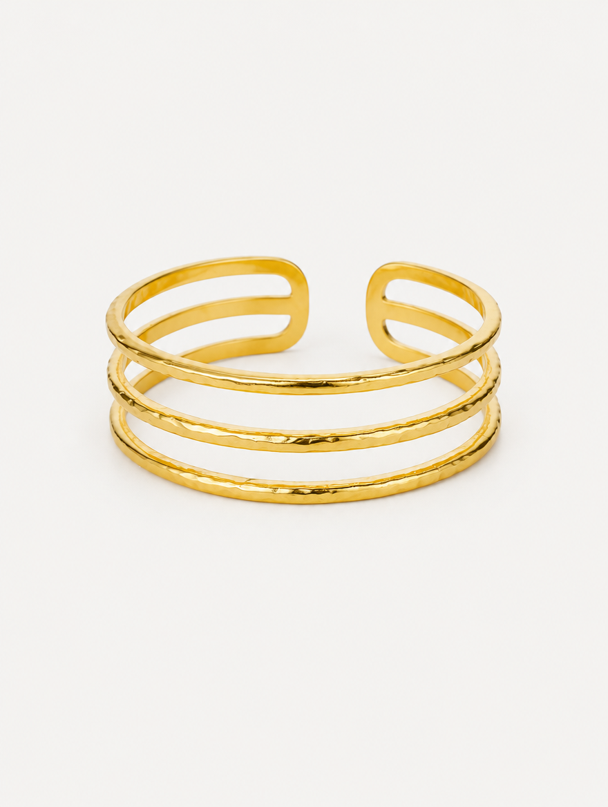 Gold triple line open cuff bracelet on a neutral background
