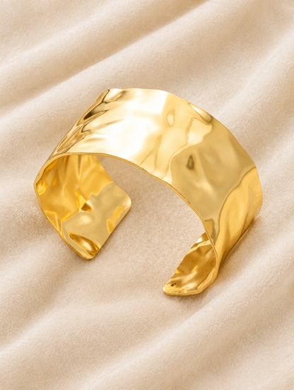 Wide gold cuff bracelet on cream velvet