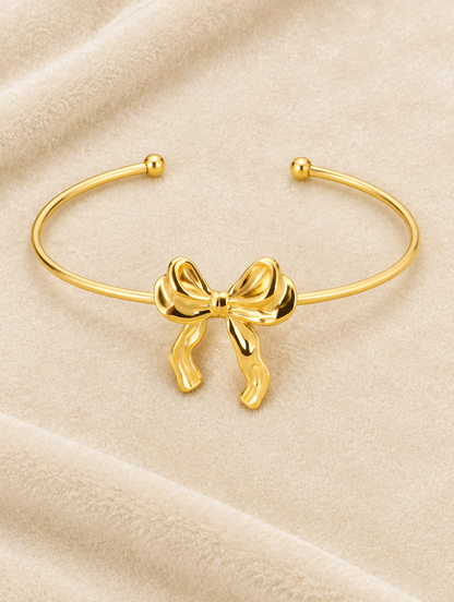 Gold bow cuff bracelet on cream velvet