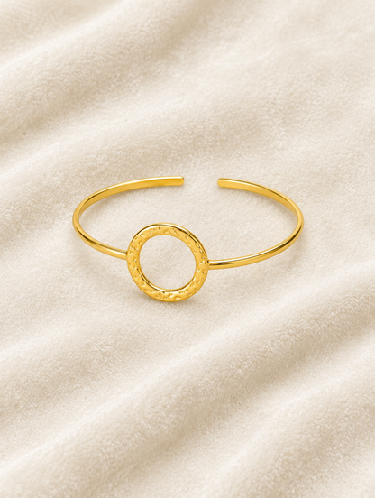 Gold circle cuff bracelet on cream velvet