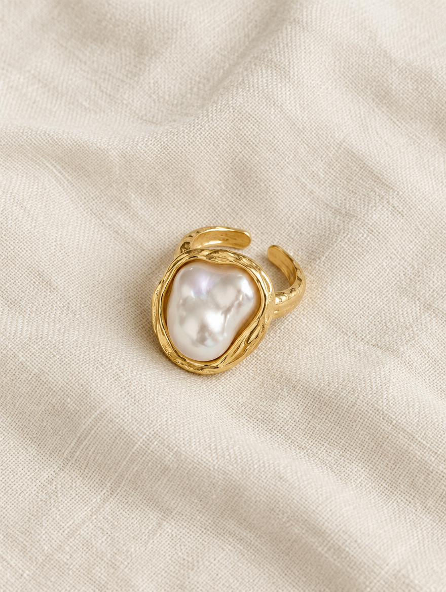 Gold textured baroque pearl ring resting on a soft textured surface