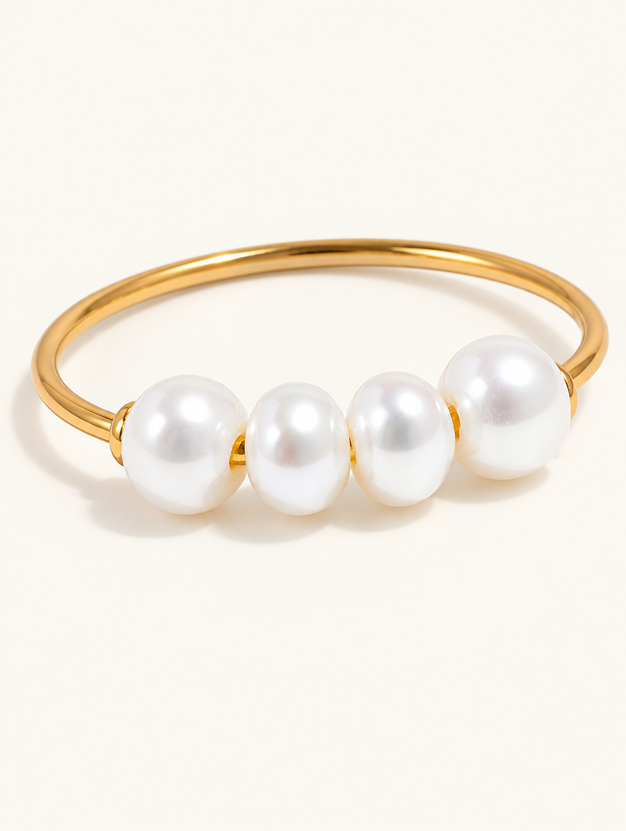 Gold thin band ring with four pearls on a neutral background