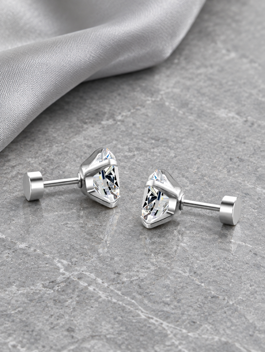 Silver claw-set cz stud earrings lying flat on a soft styled surface