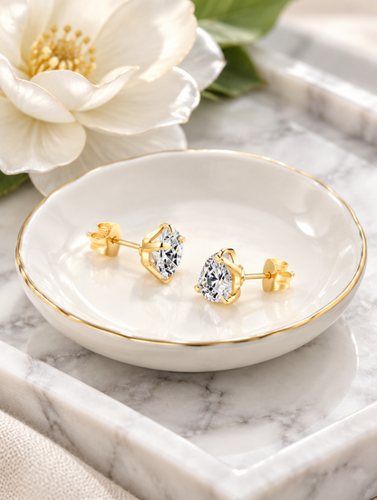 Gold claw-set cz stud earrings in a styled still life with props