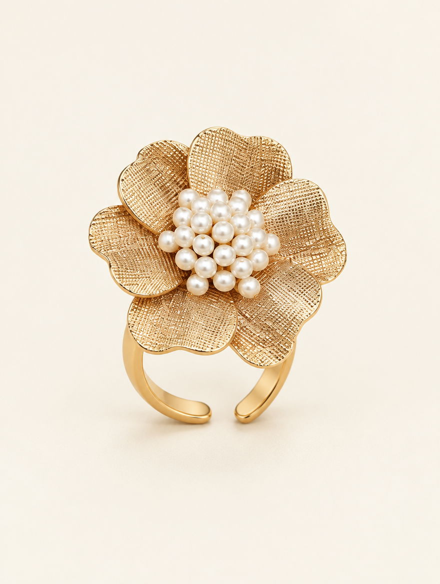 Gold textured flower ring with pearl centre on a neutral background