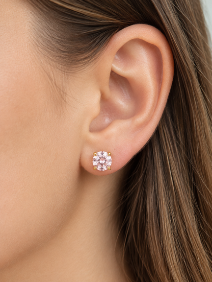 Woman wearing a gold twist-back stud earring with pink stone