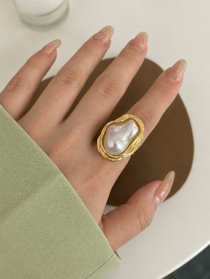 Woman wearing a gold textured baroque pearl ring on her finger