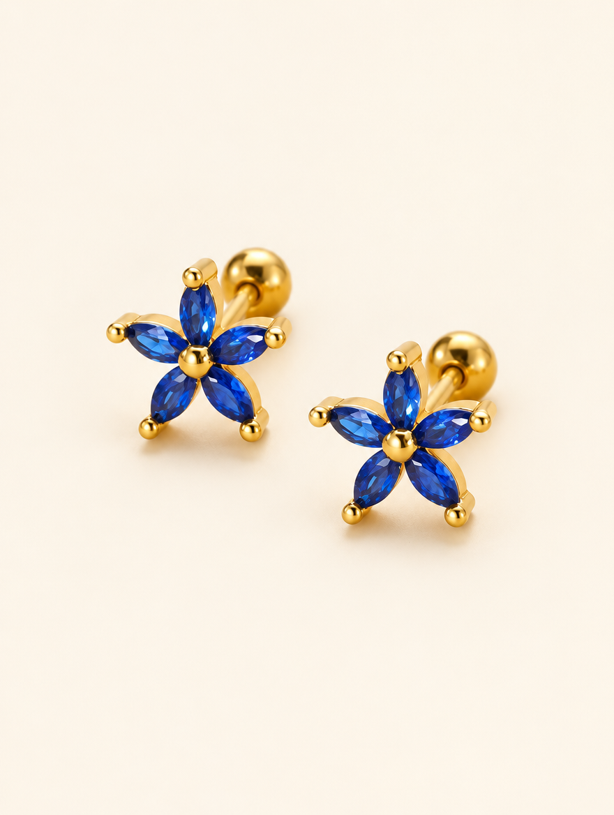 Pair of gold blue flower stud earrings on a warm off-white background