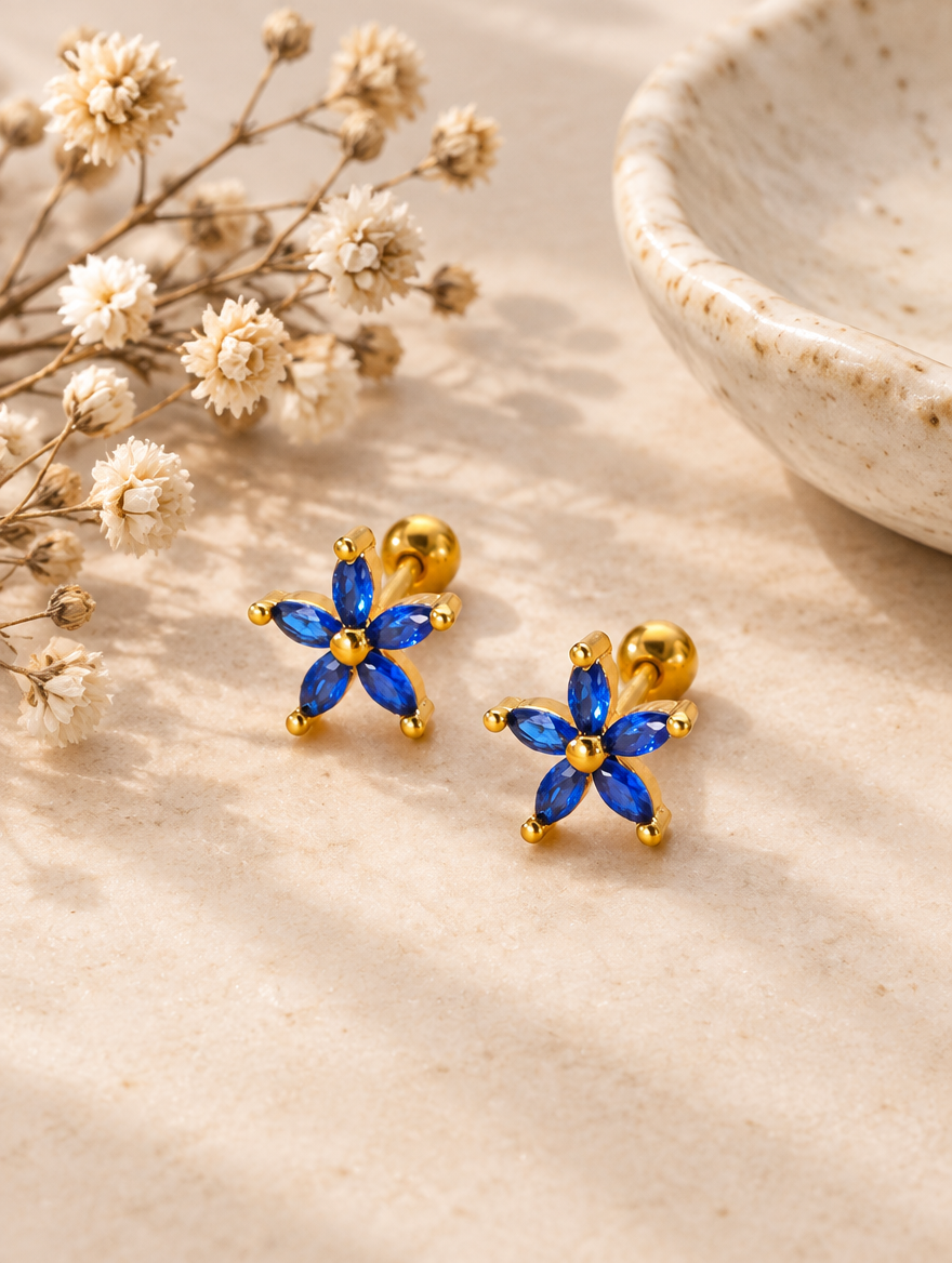 Gold blue flower stud earrings in a styled still life with props