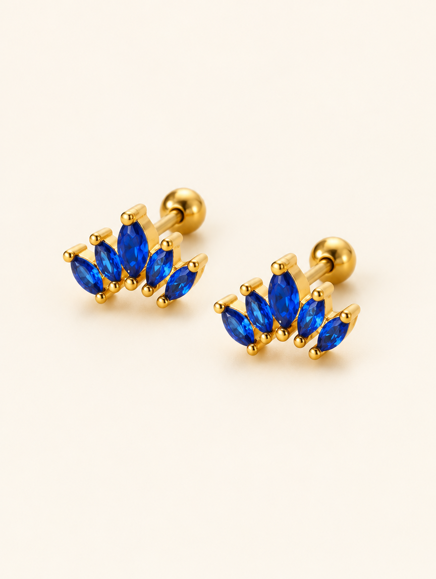 Pair of gold blue marquise fan stud earrings on a warm off-white background