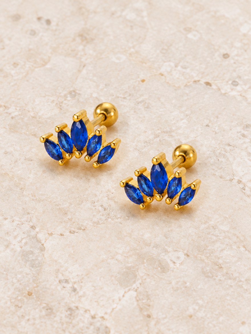 Gold blue marquise fan stud earrings lying flat on a soft styled surface