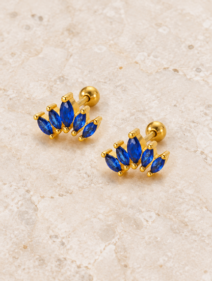 Gold blue marquise fan stud earrings lying flat on a soft styled surface