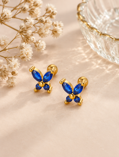 Gold blue butterfly stud earrings in a styled still life with props