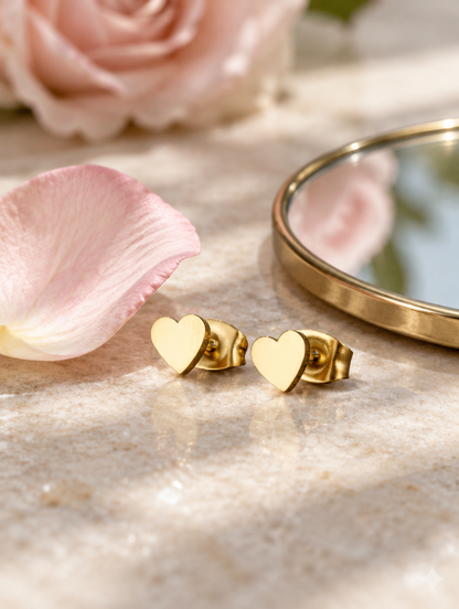 Gold heart stud earrings in a styled still life with props
