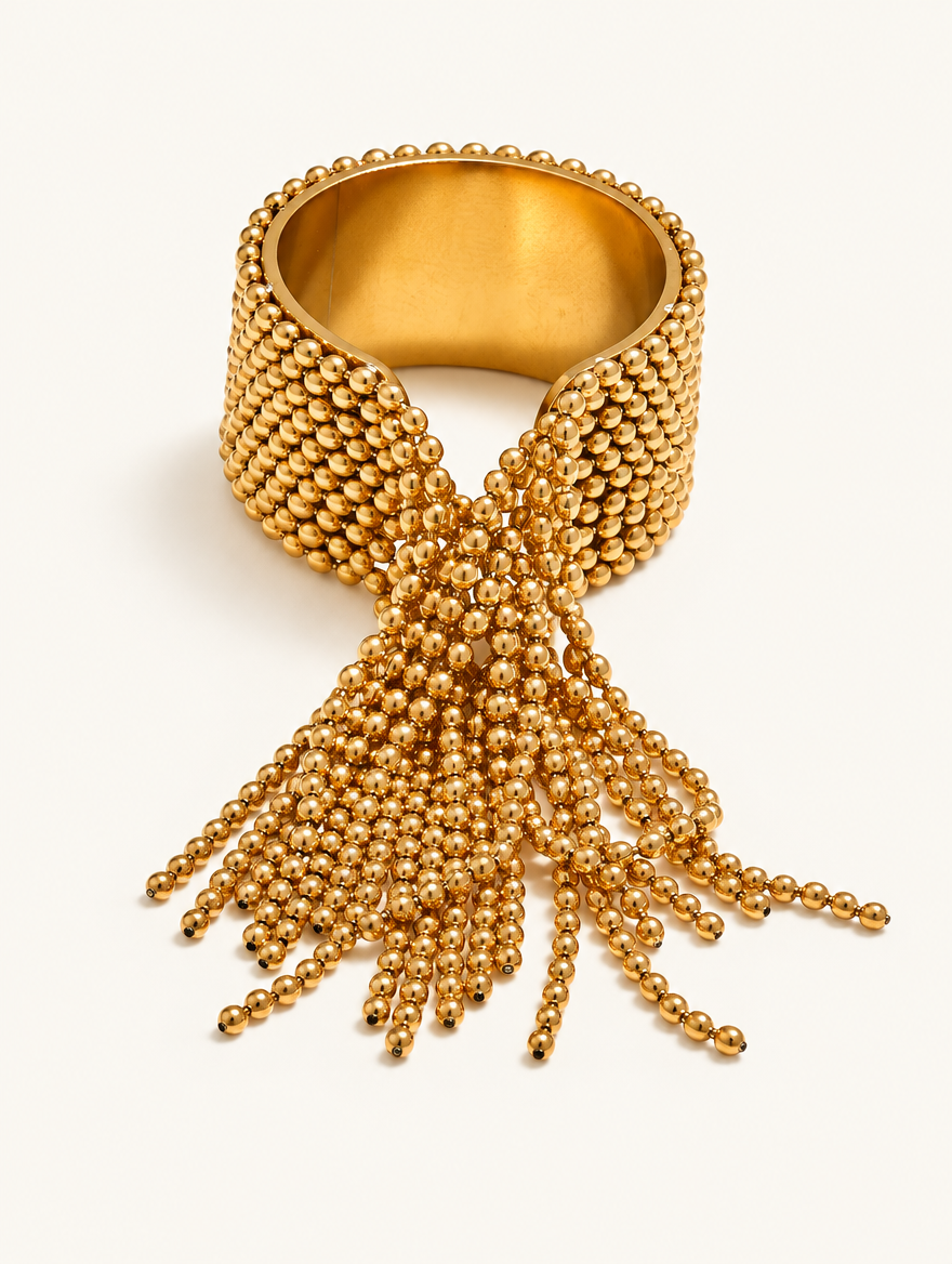 Gold ball chain tassel ring on a neutral background