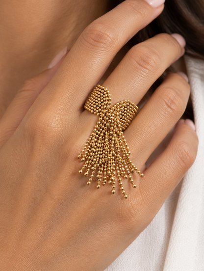Woman wearing a gold ball chain tassel ring on her finger