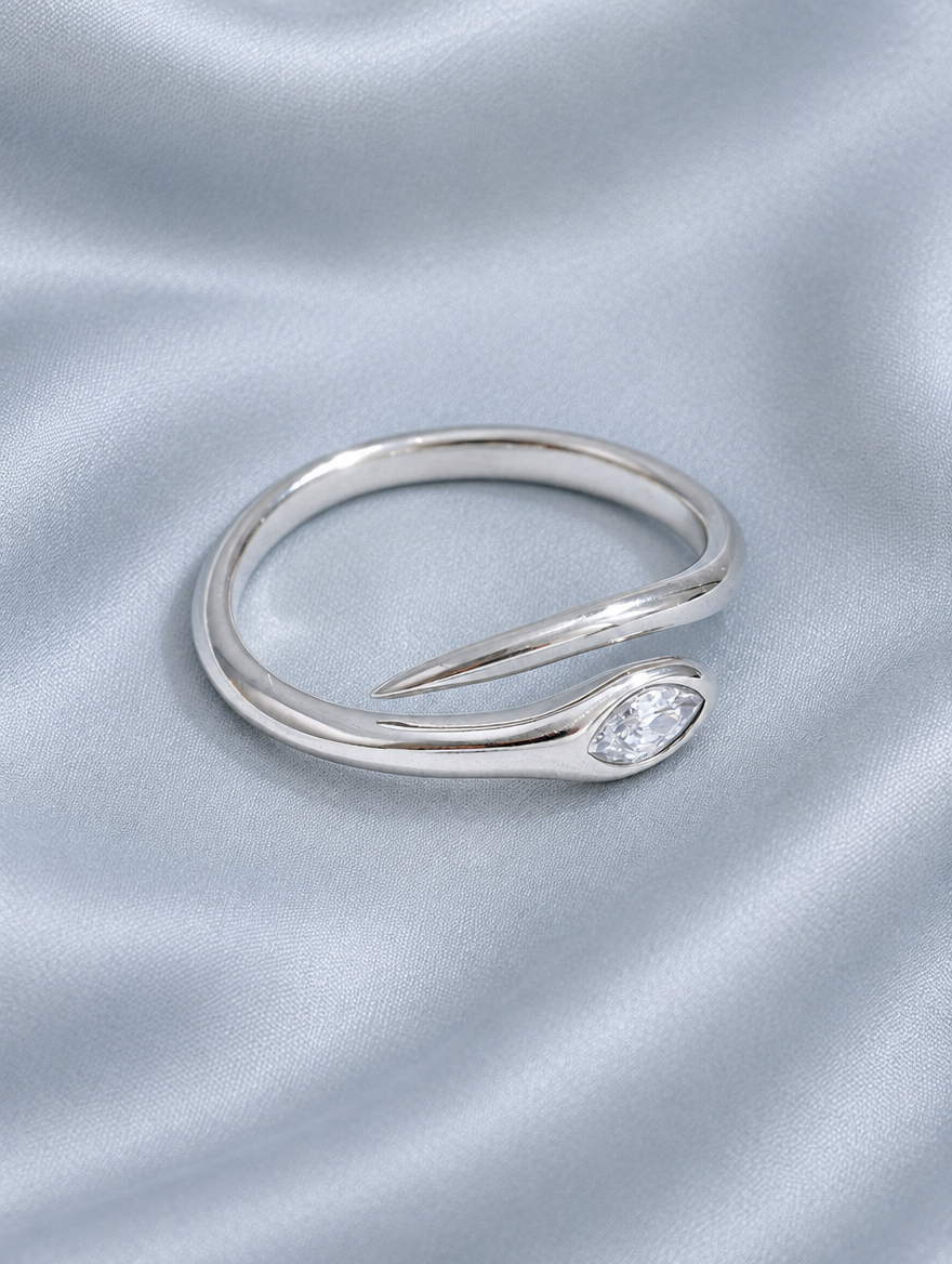 Silver snake head zirconia ring resting on a soft textured surface