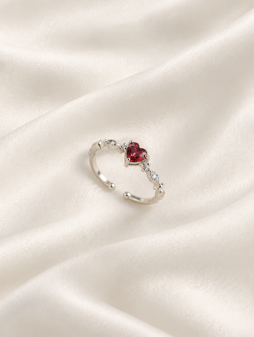 Silver red heart crystal ring resting on a soft textured surface