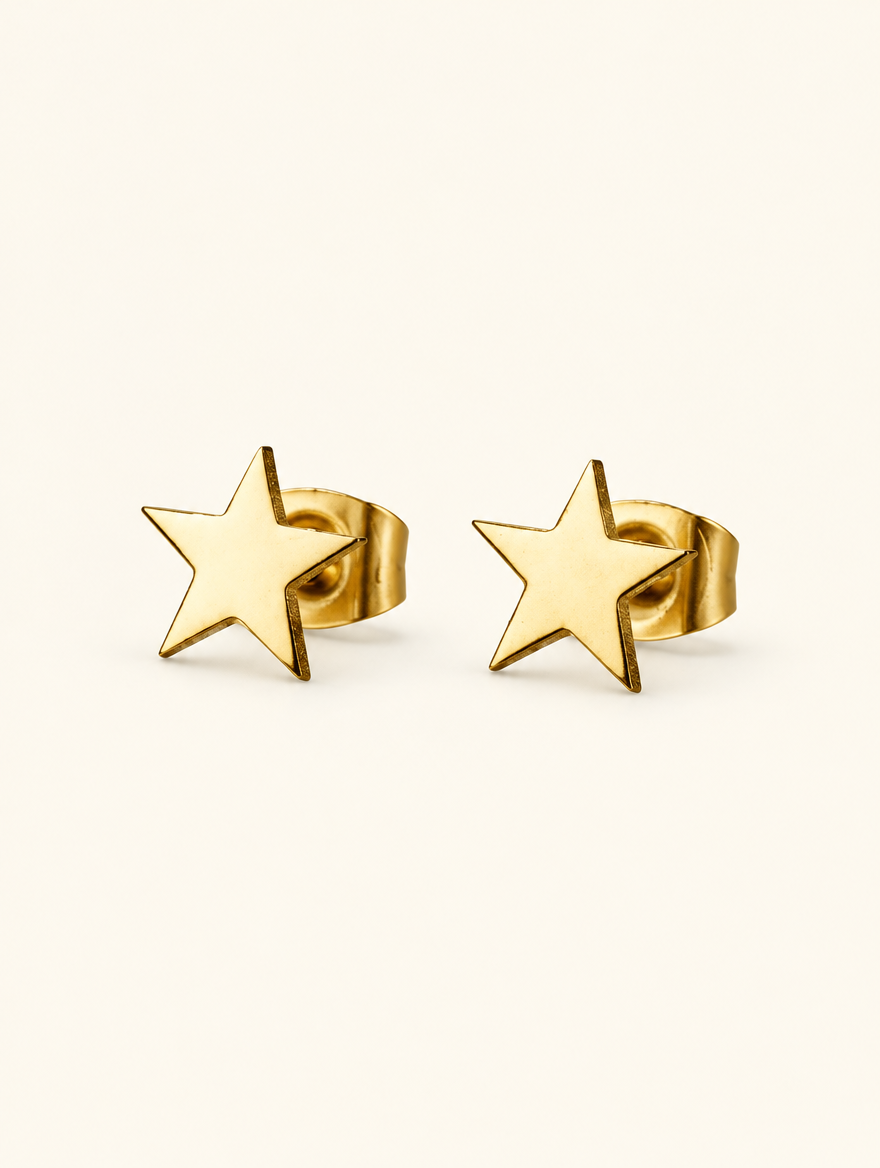 Pair of gold star stud earrings on a warm off-white background