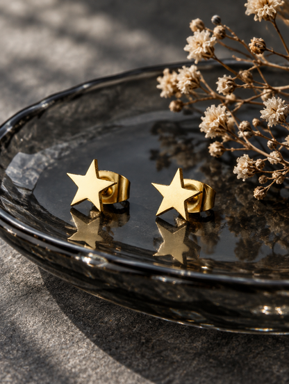 Gold star stud earrings in a styled still life with props