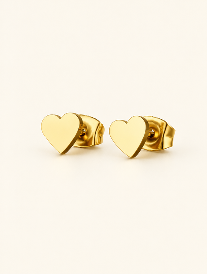 Pair of gold heart stud earrings on a warm off-white background