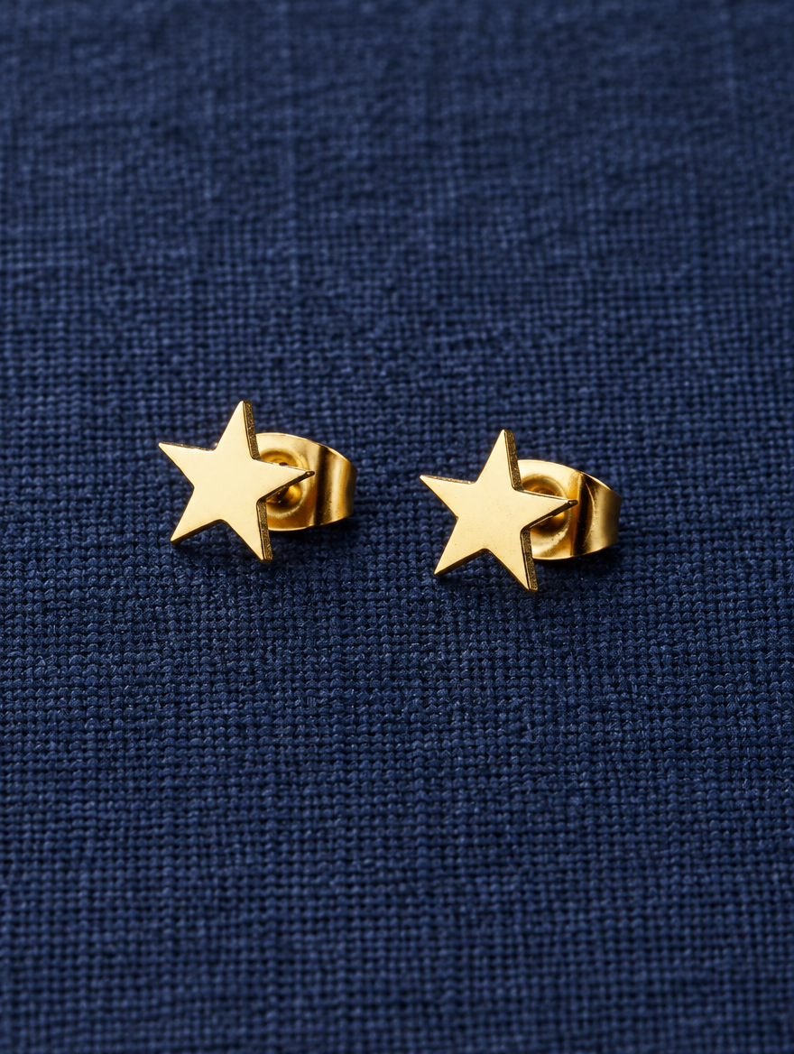 Gold star stud earrings lying flat on a soft styled surface