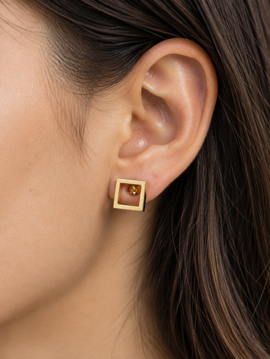 Woman wearing a gold open square stud earring