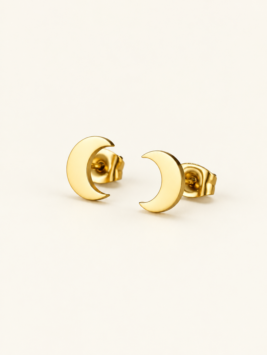 Pair of gold crescent moon stud earrings on a warm off-white background