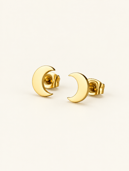 Pair of gold crescent moon stud earrings on a warm off-white background