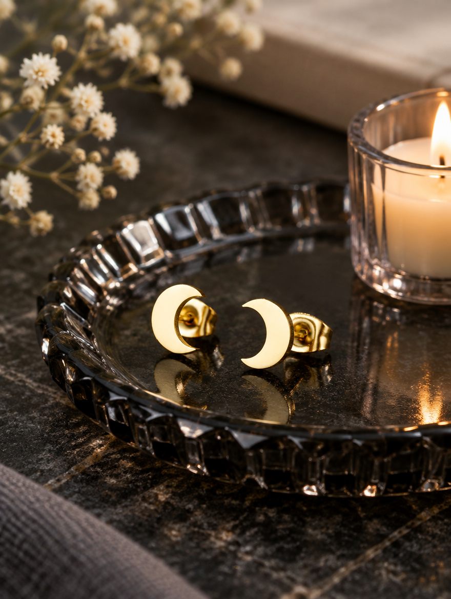 Gold crescent moon stud earrings in a styled still life with props