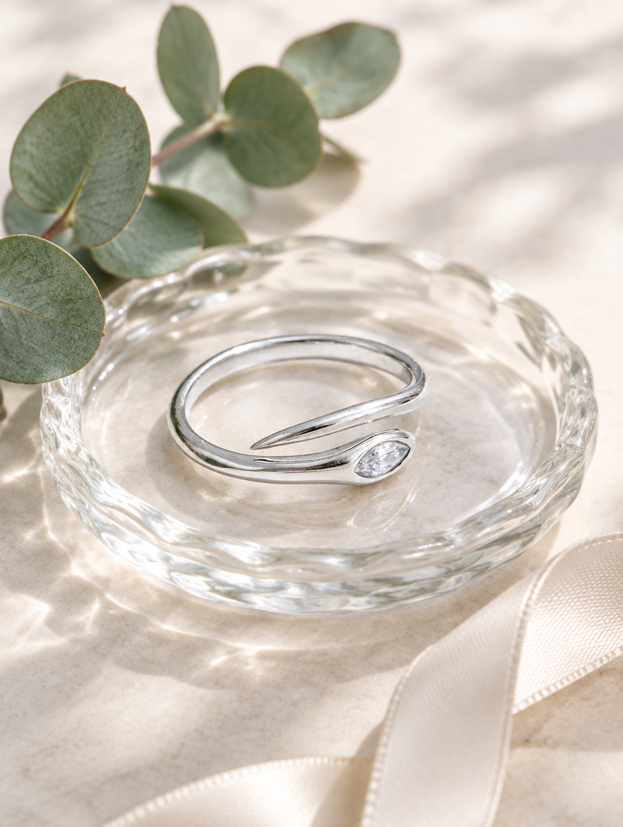 Silver snake head zirconia ring in a small dish with styling props