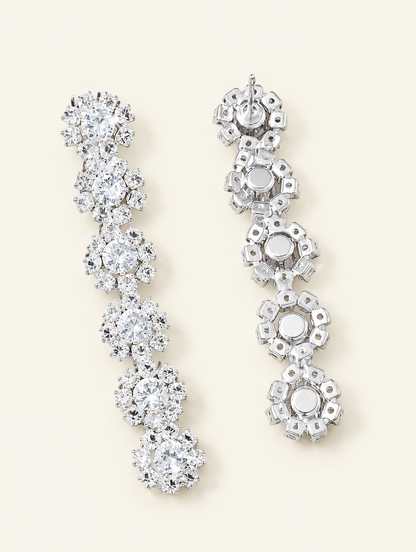 Pair of silver floral crystal long drop earrings on a warm off-white background