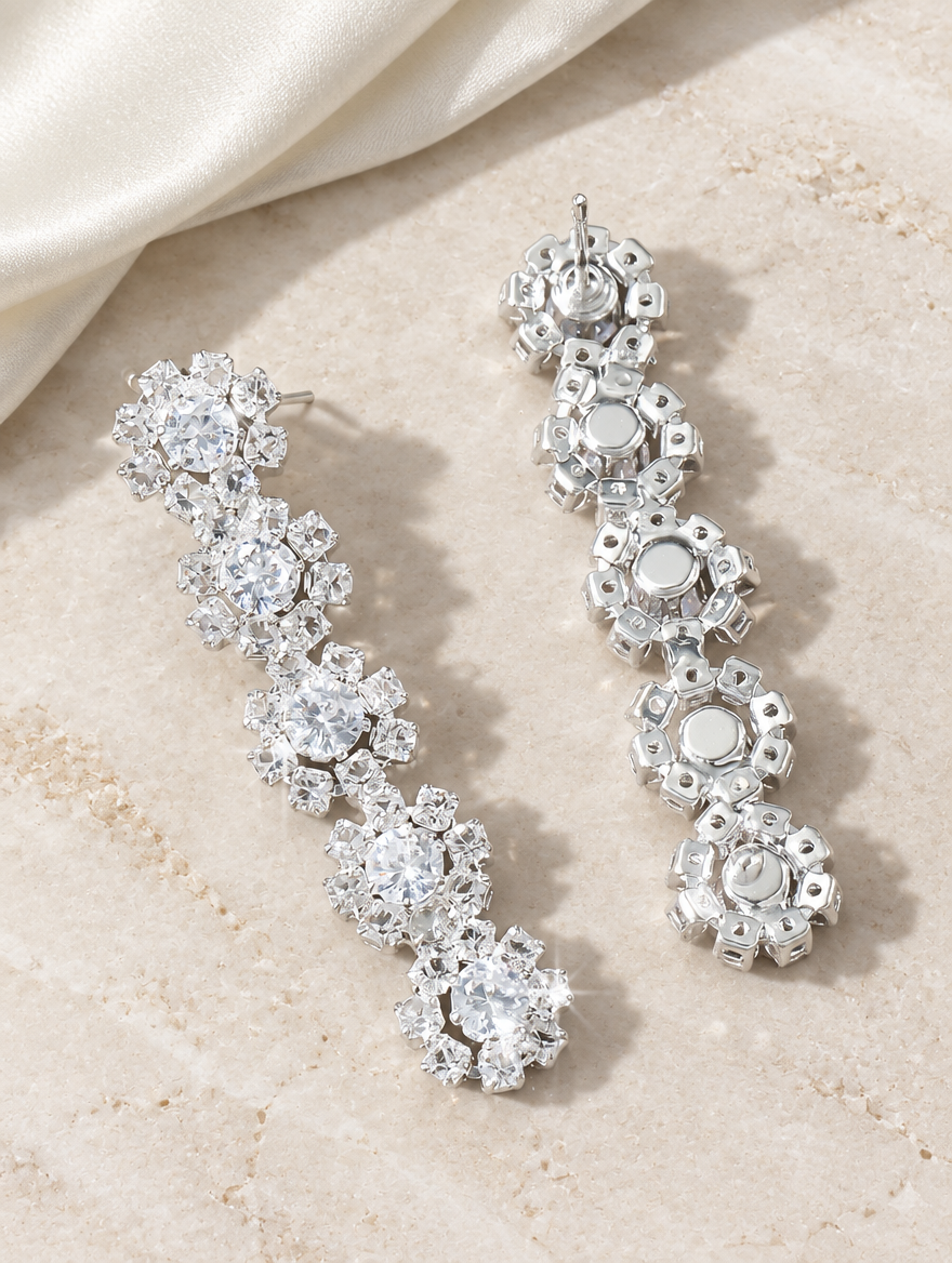 Silver floral crystal long drop earrings lying flat on a soft styled surface