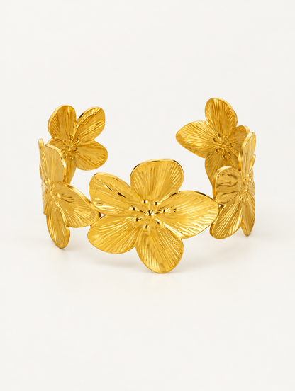 Gold flower open cuff bracelet on a neutral background