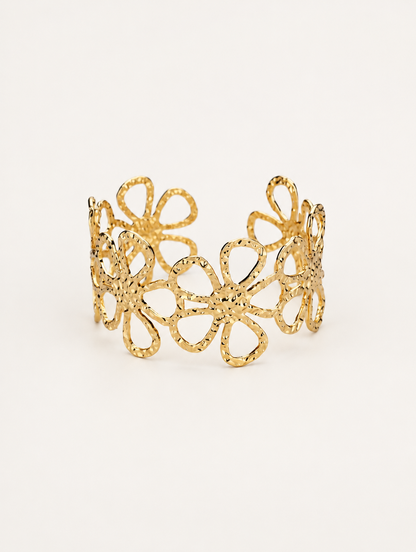 Gold outline flower openwork cuff bracelet on a neutral background