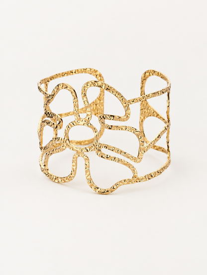 Gold wavy openwork cuff bracelet on a neutral background