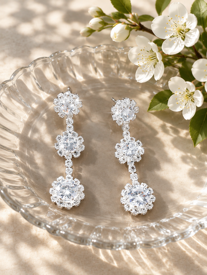 Silver three-flower crystal drop earrings in a styled still life with props