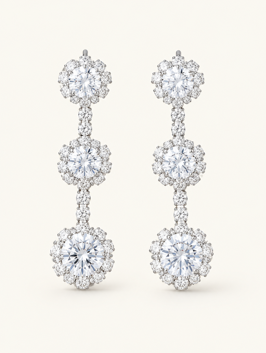 Pair of silver three-flower crystal drop earrings on a warm off-white background