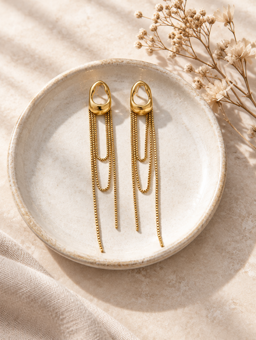 Gold chain tassel drop earrings with pearl-look bead in a styled still life with props