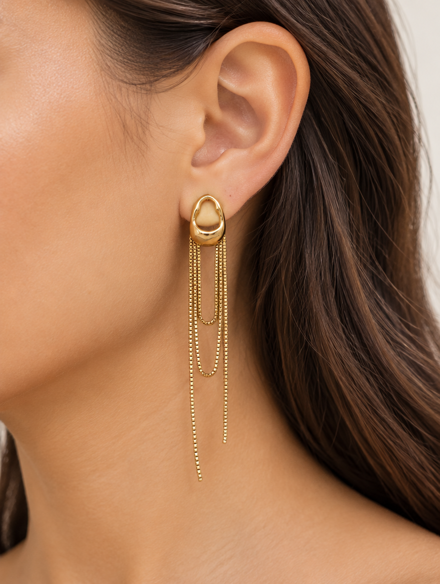 Woman wearing a gold chain tassel drop earring with pearl-look bead