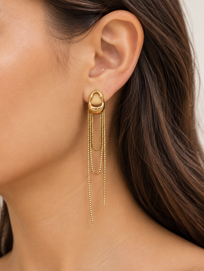Woman wearing a gold chain tassel drop earring with pearl-look bead