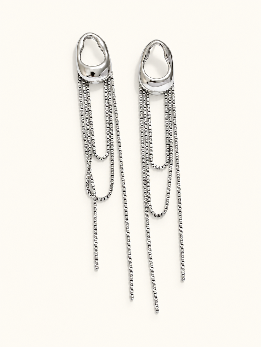 Pair of silver chain tassel drop earrings with pearl-look bead on a warm off-white background