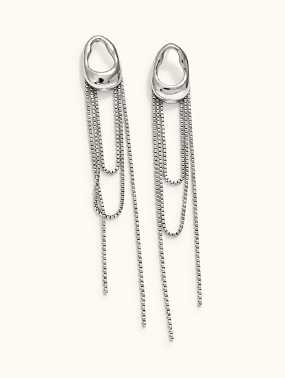 Pair of silver chain tassel drop earrings with pearl-look bead on a warm off-white background