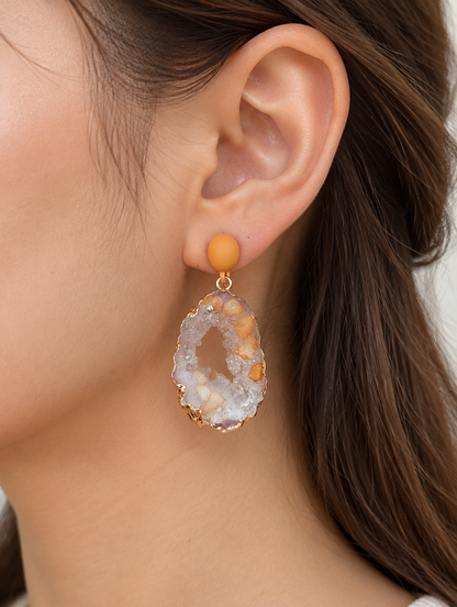 Woman wearing a orange stone-look drop earring with gold-tone edge