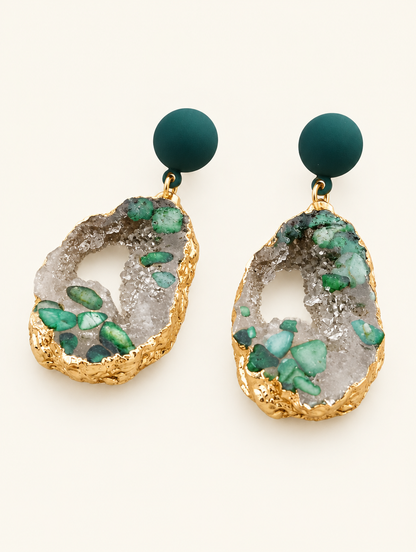 Pair of green stone-look drop earrings with gold-tone edge on a warm off-white background